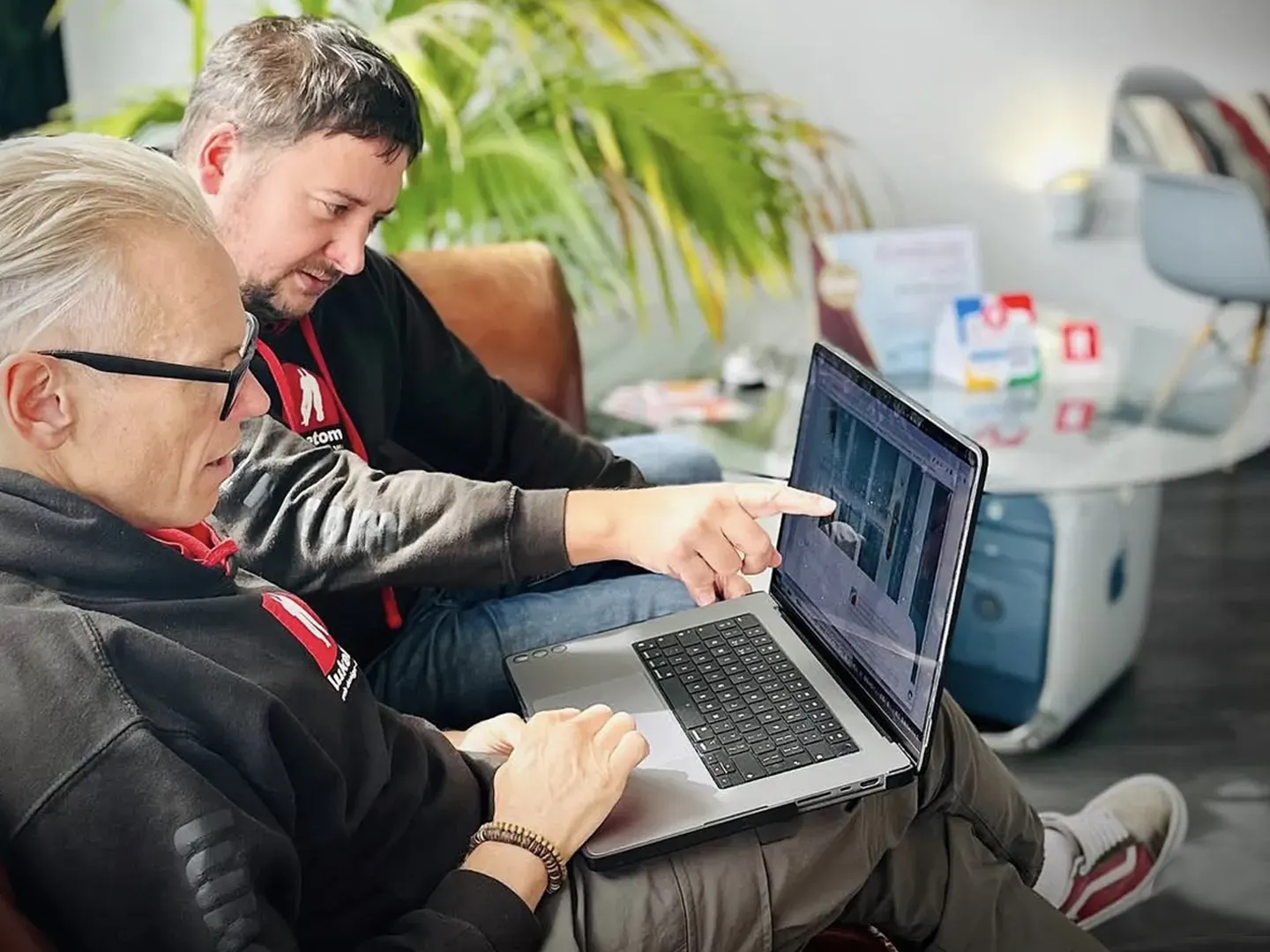 Two LukeTom team members reviewing a digital product on a laptop